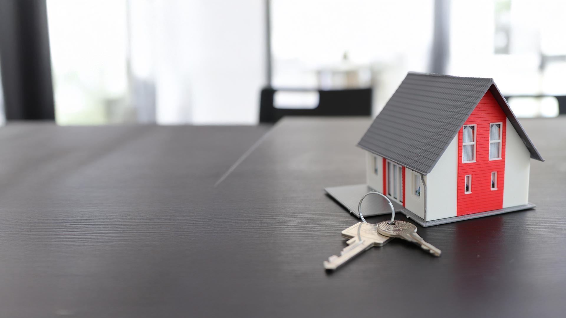 Hausmodell mit Schlüssel auf einem Tisch – Informationen zum Glasfaseranschluss für Hauseigentümer in Baden und Ennetbaden von Baden4net